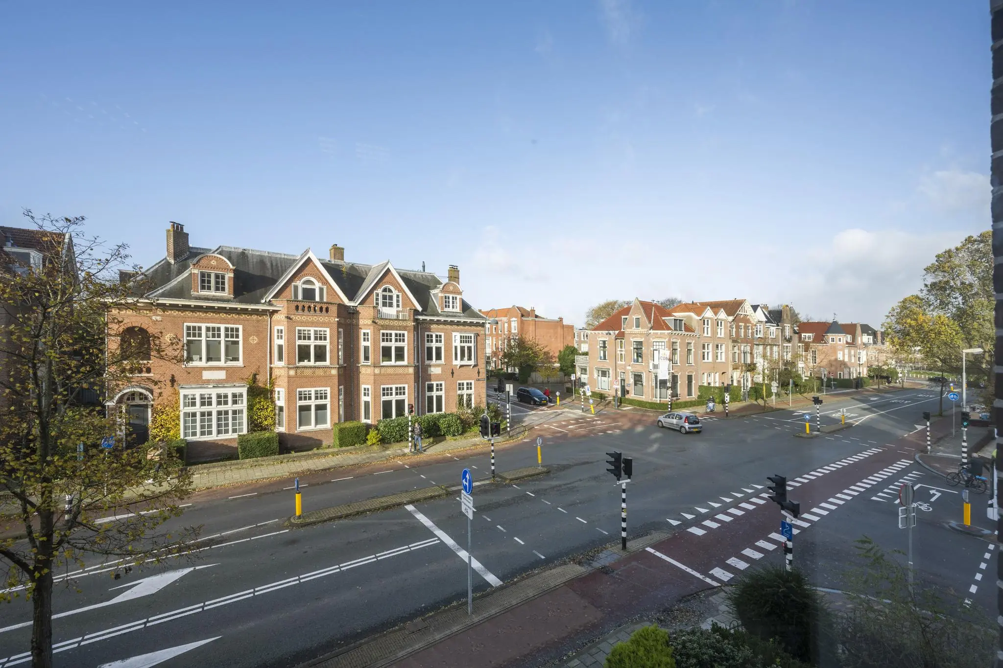 Straatbeeld van de Van Eedenstraat met karakteristieke bakstenen herenhuizen en een kruispunt met verkeerslichten.